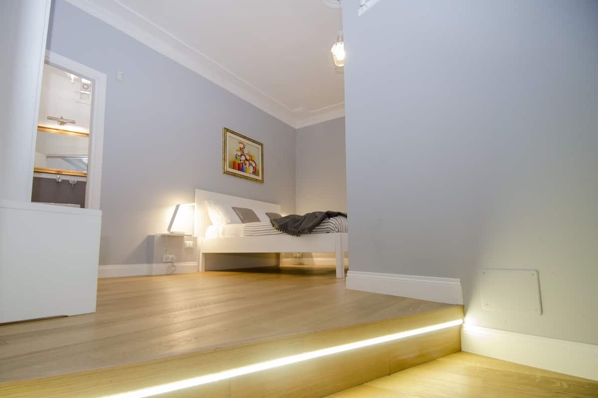 A bedroom with a bed, bedside table, and a painting on the wall.