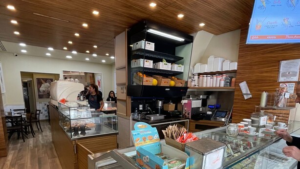 A bakery with a display case filled with pastries and a coffee machine. - Room Inn Vatican (Rome)