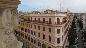 A multi-story building with a pink facade, large windows, and balconies. - Room Inn Vatican (Rome)