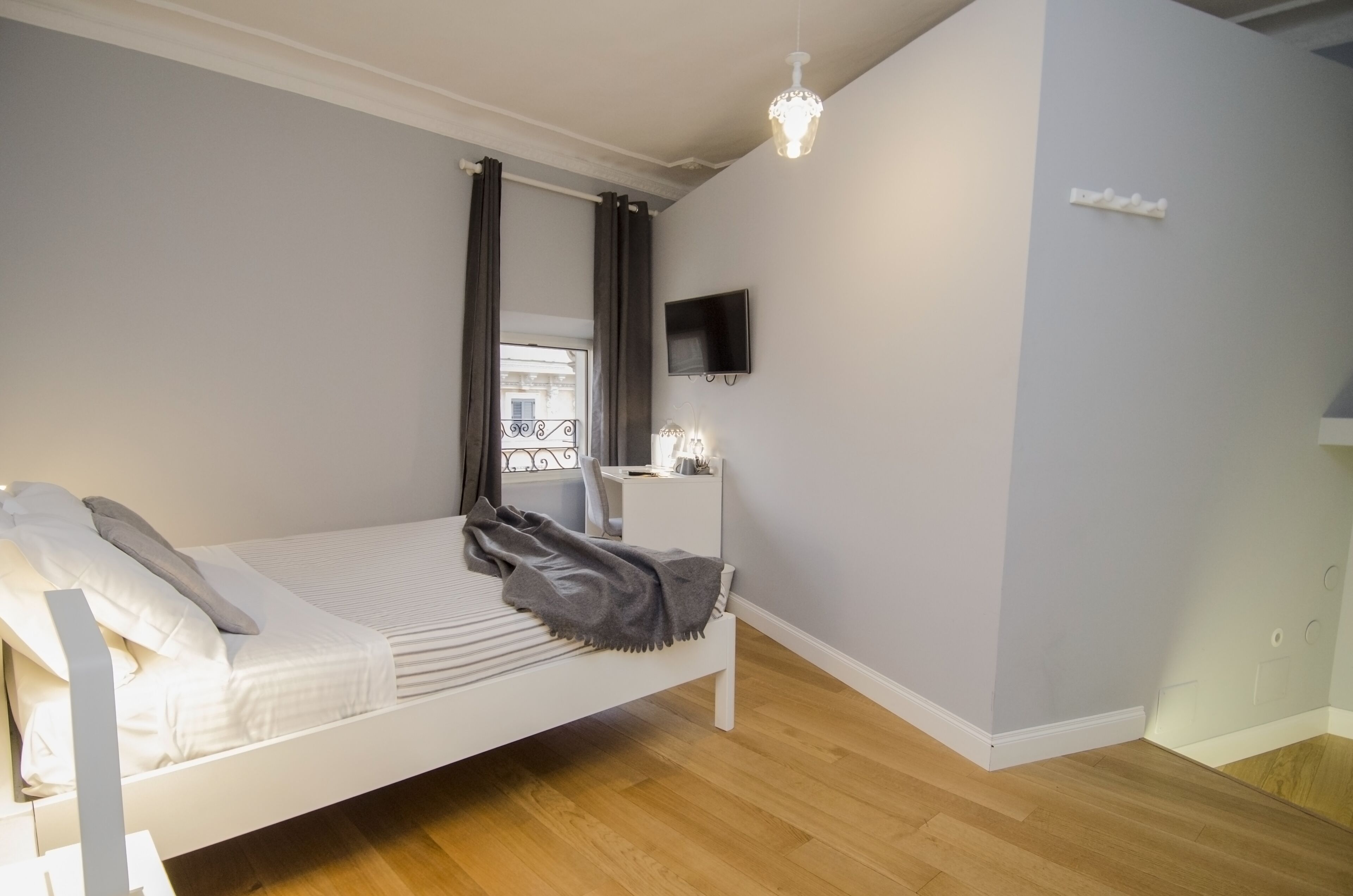 Un dormitorio moderno con una cama individual, una mesita de noche, un televisor y una ventana con cortinas.