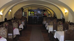 A restaurant with an arched ceiling, wooden chairs with patterned upholstery, and tables covered with white tablecloths. - Hotel York (Plzen)