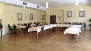 A large room with long tables and chairs, white ceiling fans, and framed artwork on the walls. - Hotel York (Plzen)