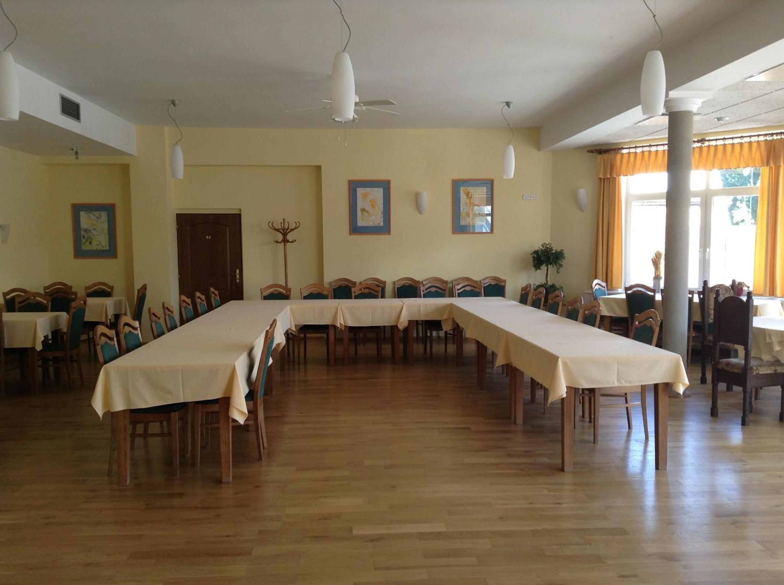 Un gran comedor con largas mesas, sillas de madera y ventiladores de techo.