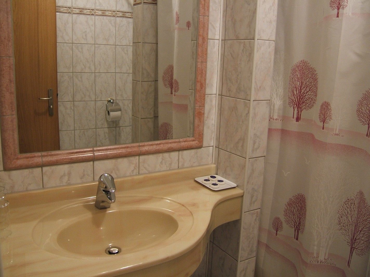 Un baño con lavamanos, espejo y paredes de azulejos.