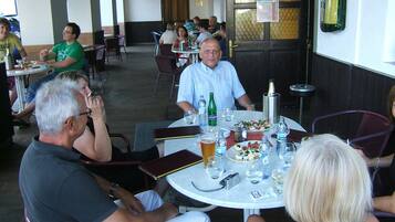 Un groupe de personnes est réuni dans un restaurant autour de tables rondes, de chaises et de différentes décorations de table, notamment des assiettes, des verres et des bouteilles.