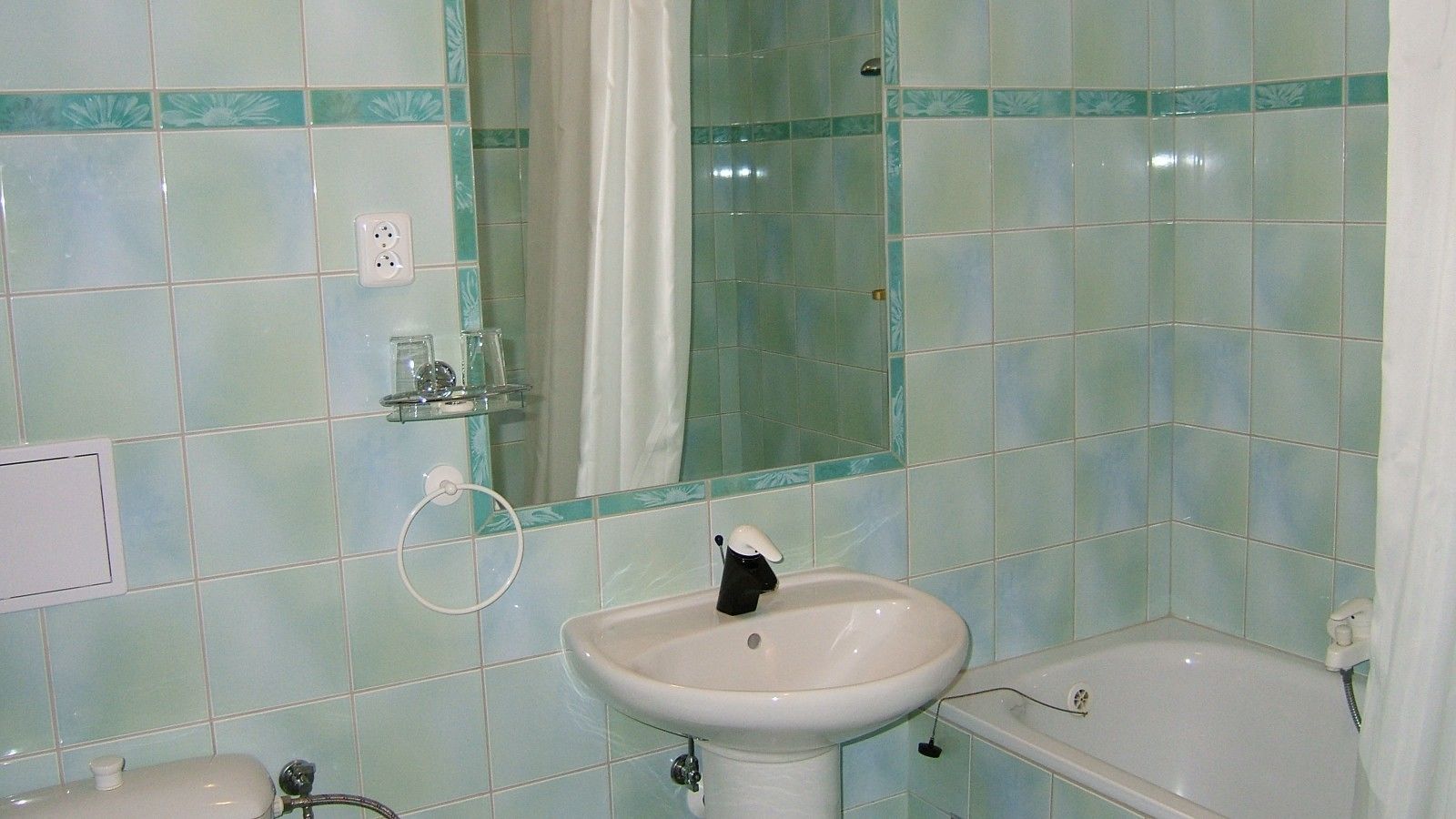 A bathroom with a sink, mirror, and bathtub.