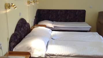 A hotel room with two beds, a headboard, and a bedside table.