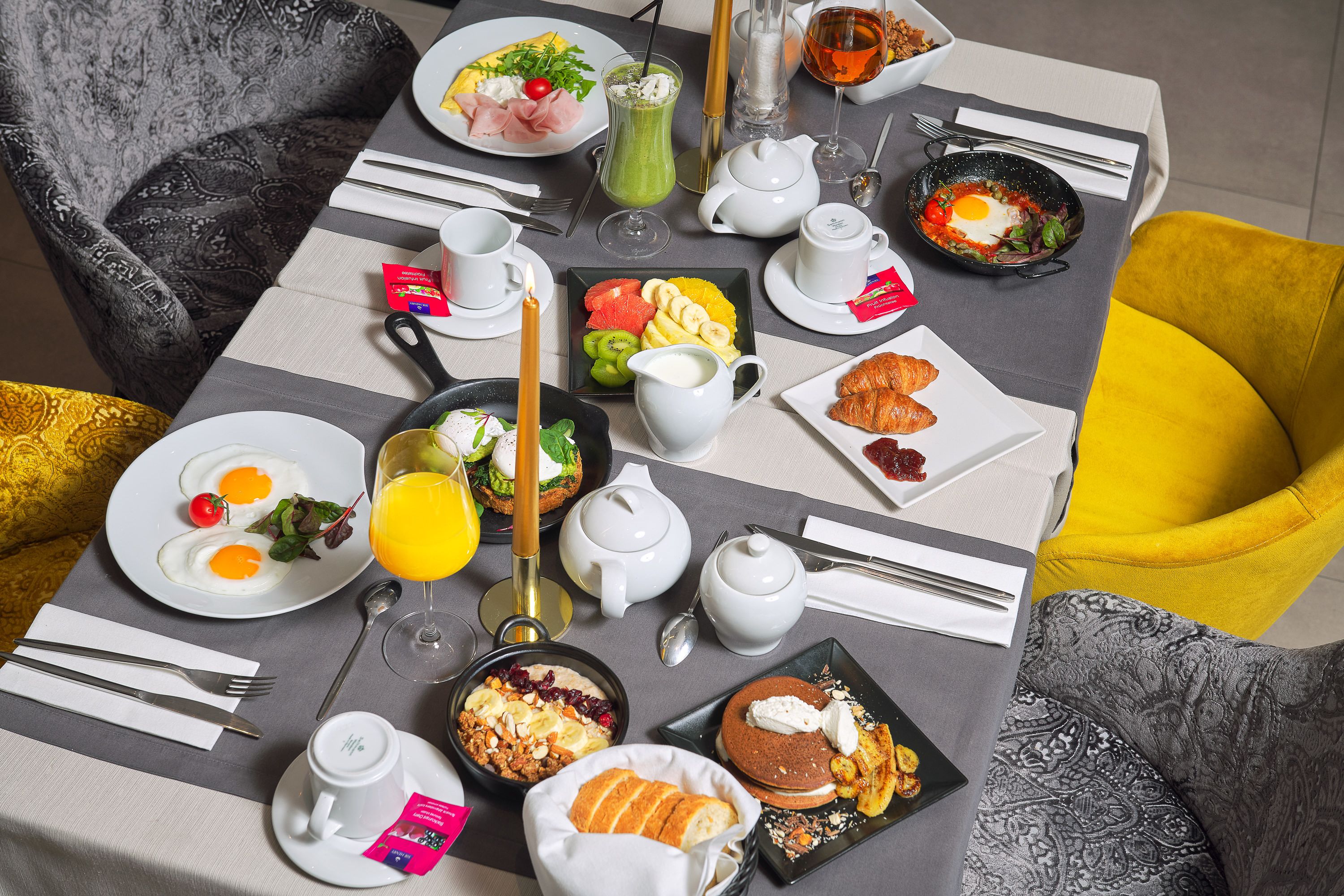 A breakfast table with various dishes, including eggs, toast, and fruit.