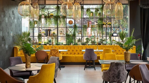 A restaurant with yellow sofas, round tables, and hanging light fixtures. - Sia Split Hotel (Split)