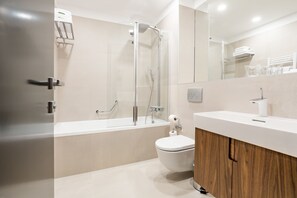 A modern bathroom with a glass-enclosed shower, a white toilet, and a wooden vanity.