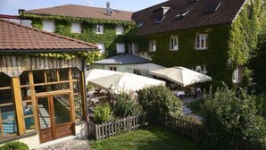 A traditional European-style building with a courtyard, wooden fences, and outdoor seating areas. - Hôtel le Pré Serroux (Champagney)