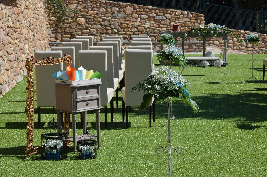 A seating area with white chairs and a table with a decorative frame and glass containers.