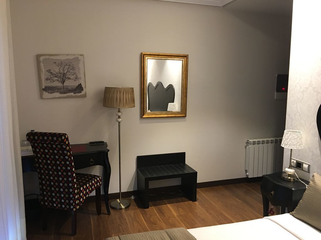 A room with a desk, chair, lamp, and a framed artwork on the wall.