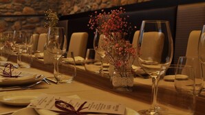 Une table à manger élégamment dressée, avec des verres à vin, des assiettes et un centre de table composé de fleurs séchées.