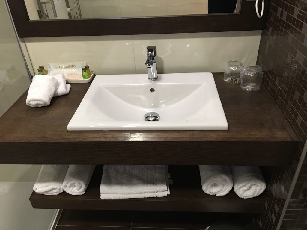 A bathroom with a white sink, dark wooden vanity, and multiple towels.