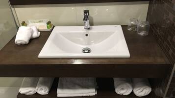 A bathroom with a white sink, dark wooden vanity, and multiple towels.