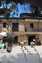 Un restaurante con terraza, una sombrilla con la marca Coca-Cola y plantas decorativas.