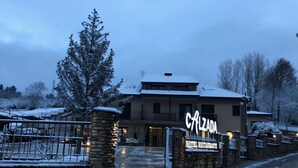 Un hôtel avec une entrée en pierre, une enseigne indiquant « Calzada Hotel Restaurant », et un environnement enneigé.
