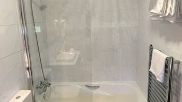 Un baño moderno con ducha envuelta en vidrio, bañera y perchero.