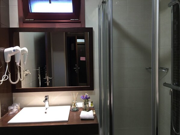Un baño con lavamanos blanco, un espejo y un secador de pelo en la pared.