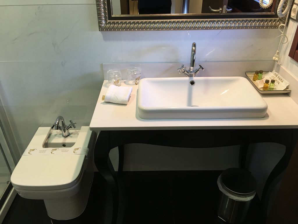 A bathroom with a white sink, a mirror, and a bidet.