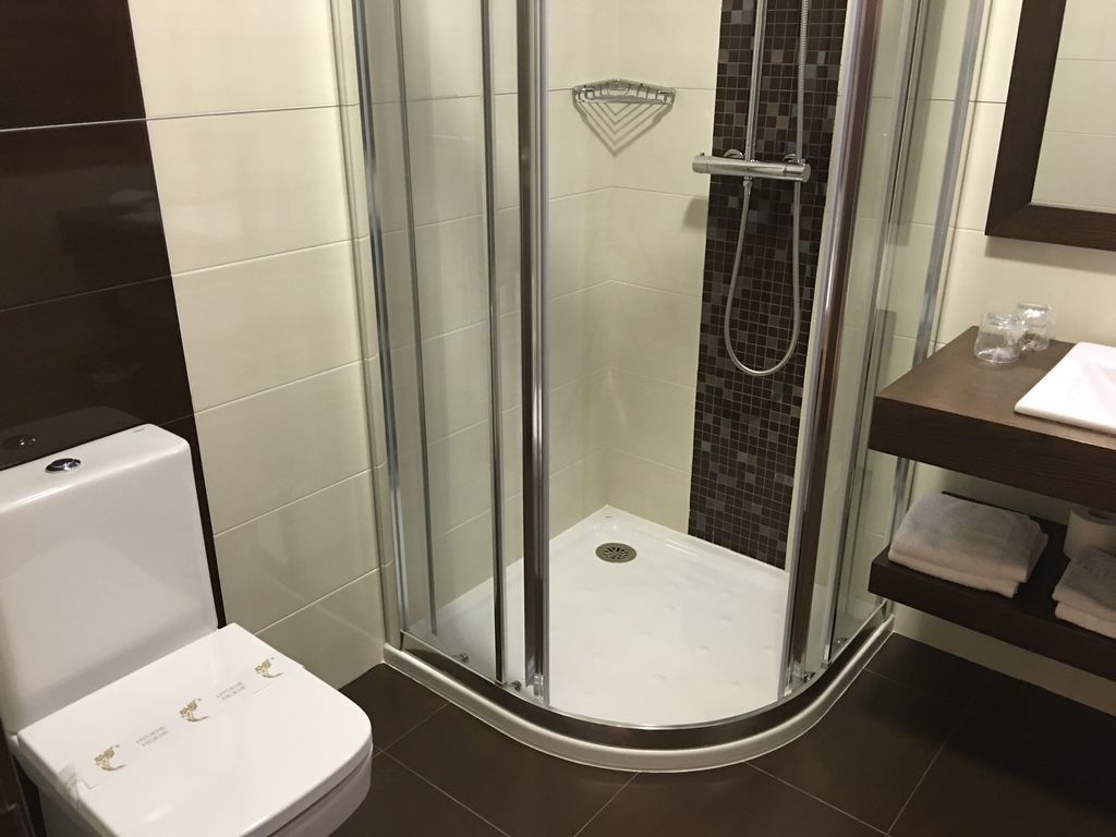 Een moderne badkamer met een douchecabine van glas, een wit toilet en een donkere betegelde vloer.