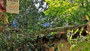 A sign for 'Hôtel Le14' amidst greenery and stone walls. - Hôtel Le Quatorze (Figeac)