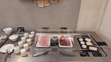 A deli counter with various meats, cheeses, and condiments.