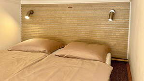 A bedroom with a bed, two pillows, a wooden headboard, and two wall-mounted lights. - Apartment Siroka 14 (Prague)