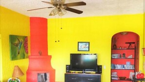 A living room with a red fireplace, a television, and a bookshelf. - Villa Meli 2 by Kivoya (Jocotepec)