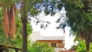 A pathway leading to a building with a tiled roof, surrounded by lush greenery and palm trees. - Villa Meli 2 by Kivoya (Jocotepec)