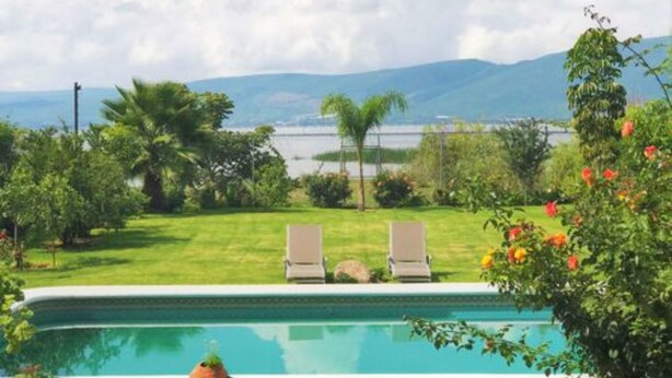 A swimming pool with two lounge chairs, surrounded by lush greenery and a view of mountains. - Villa Meli 2 by Kivoya (Jocotepec)