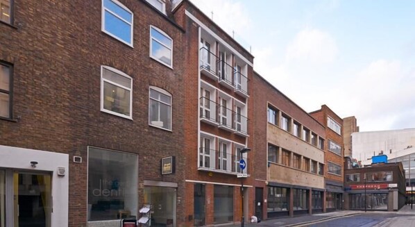 A multi-story building with a brick facade, large windows, and a ground-floor shop.