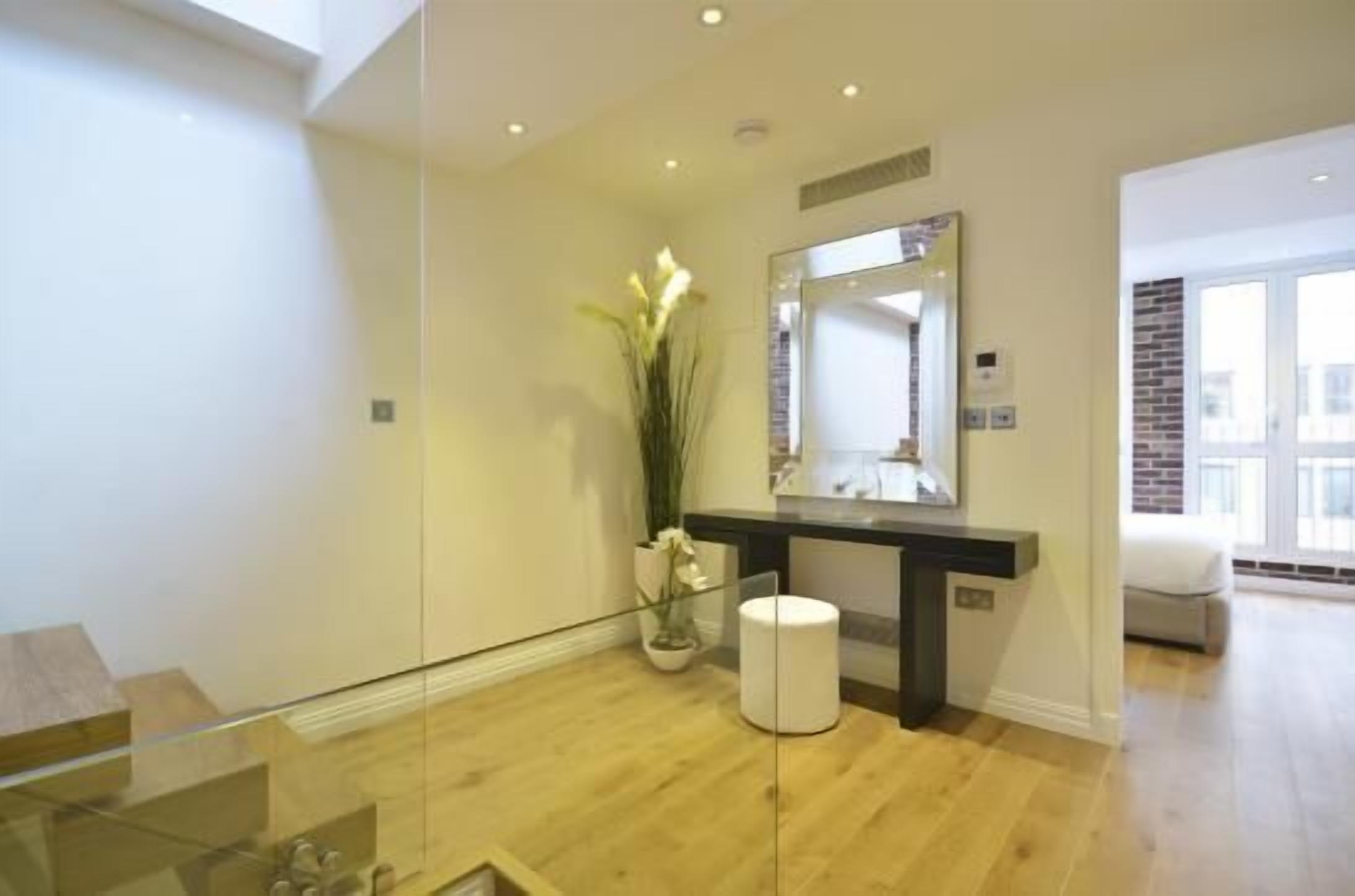 A modern bathroom with a glass shower enclosure, a large mirror, and a potted plant.