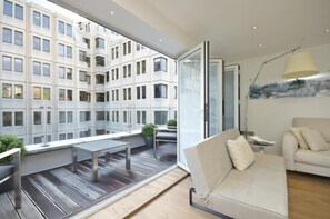 A modern apartment with a large balcony, a sofa, and a dining area.