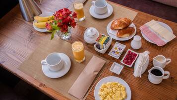 A breakfast tray with eggs, bread, jam, and coffee on a wooden table.
