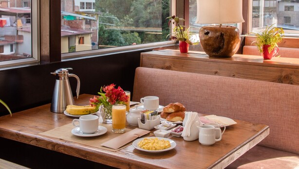 A breakfast table with a view of a mountainous landscape through large windows.