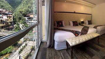 A bedroom with a large bed, a bench, and a view of a mountainous area.