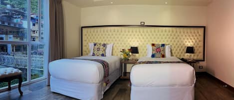 A hotel room with two beds, a large window, and a view of buildings outside.
