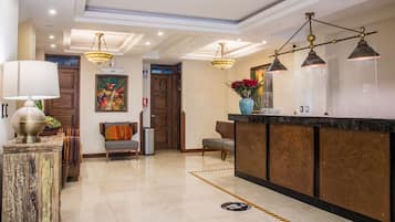 A hotel lobby with a reception desk, seating area, and decorative lighting.