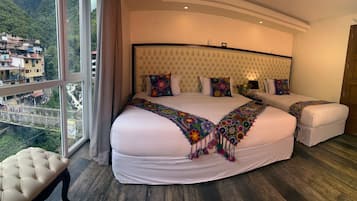 Quarto de hotel com uma cama grande, duas mesas de cabeceira e vista para uma área montanhosa.