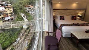 A hotel room with a large bed, a chair, and a view of a river and buildings.