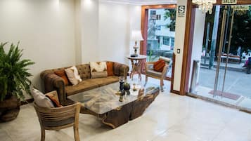 A lobby with a sofa, chairs, a coffee table, a lamp, and a sign reading "SALIDA".