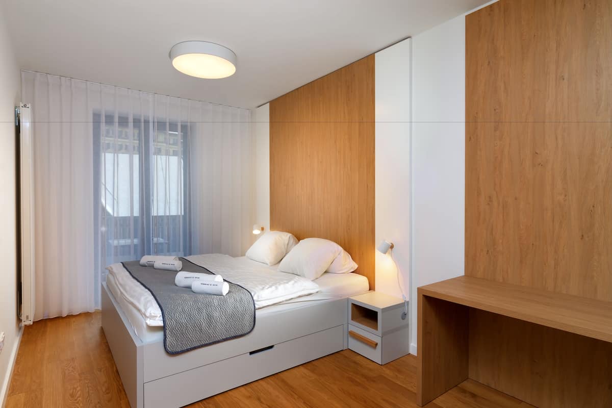 A modern bedroom with a bed, bedside tables, and a wooden panel wall.