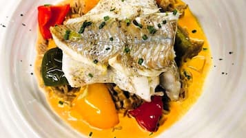 A plate of fish with vegetables and sauce.
