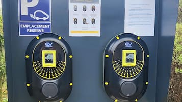 A parking station with two charging points, a reserved parking sign, and instructions for use.