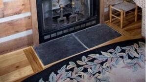 A rustic cabin interior with a fireplace, wooden walls, a framed artwork, and a small table. - River Bluff Farm Bed & Breakfast (New Market)