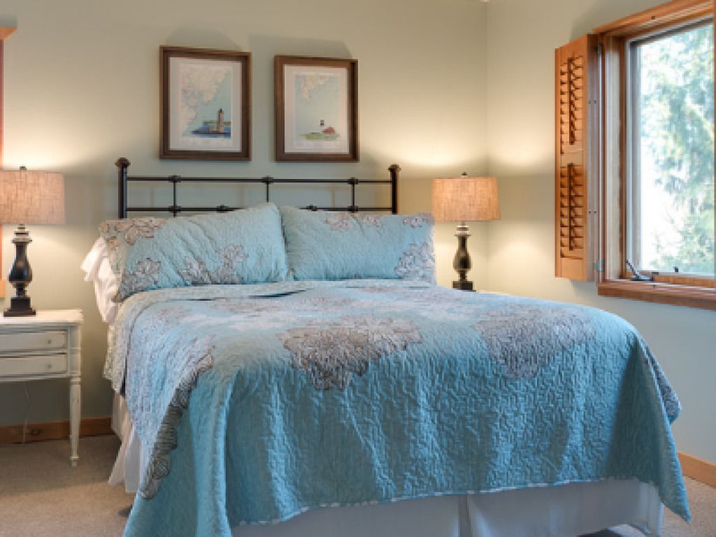 A bedroom with a bed, two bedside tables, and a window with blinds.