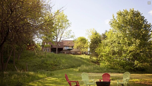 A grassy outdoor area with four Adirondack chairs and a black fire pit. - River Bluff Farm Bed & Breakfast (New Market)