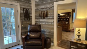 A room with a leather chair, a lamp, and a wooden wall. - Red Fox Run B&B (Cazenovia)